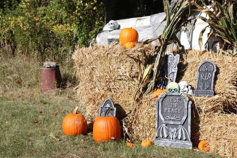 Outdoor Halloween display of pumpkins and tombstones arranged on hay bales