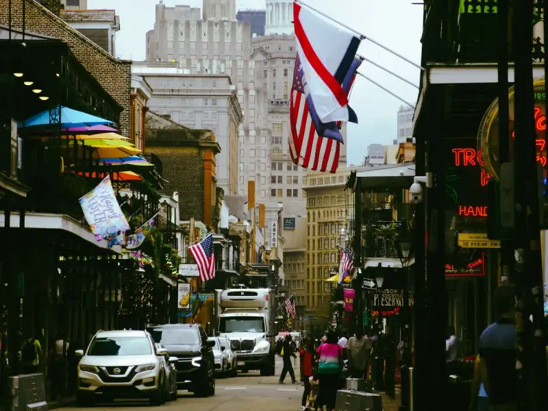 Busy French Quarter street in New Orleans with flags on balconies and people walking