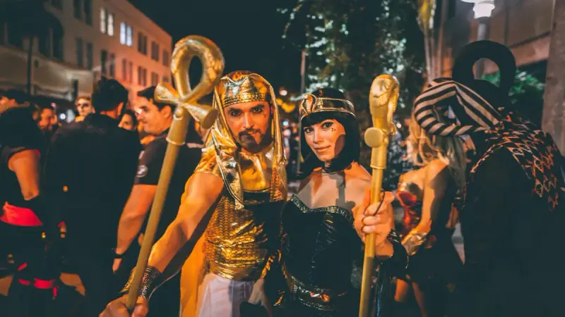 Couple in Egyptian costumes smiling at a nighttime street party