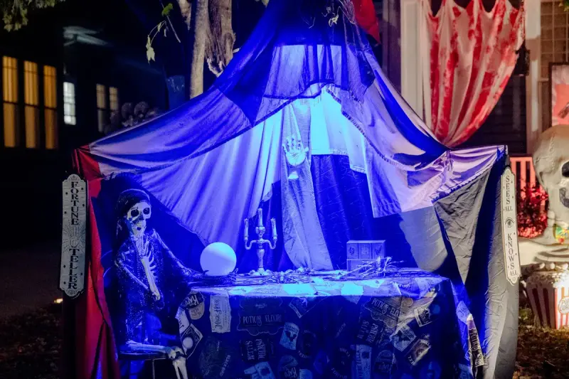 Fortune teller Halloween scene with skeletons under eerie colored lighting outside a home