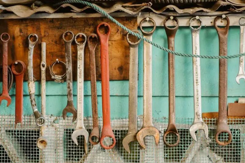 Row of steel wrenches hanging from a rope on a workshop wall