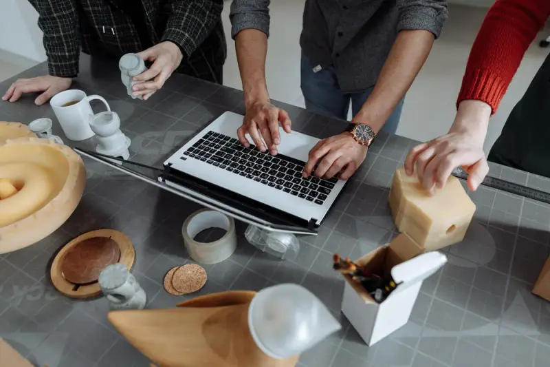 Product team around a laptop with foam and ceramic prototypes on a work table