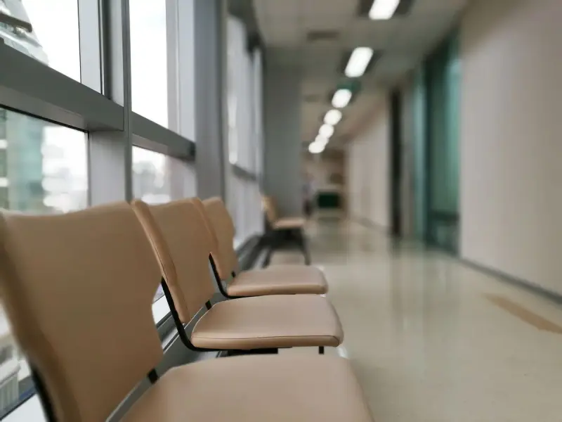 Row of empty chairs along a softly lit hospital corridor