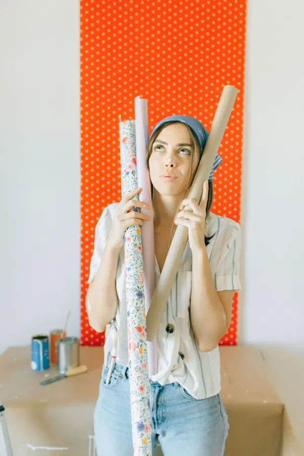Woman holding patterned wallpaper rolls while considering an interior scheme