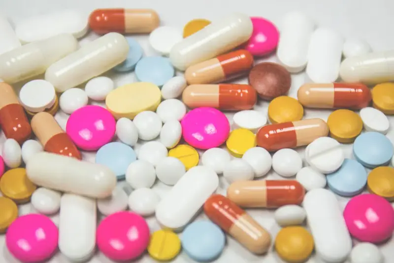 Pile of white, pink, yellow and brown tablets and capsules