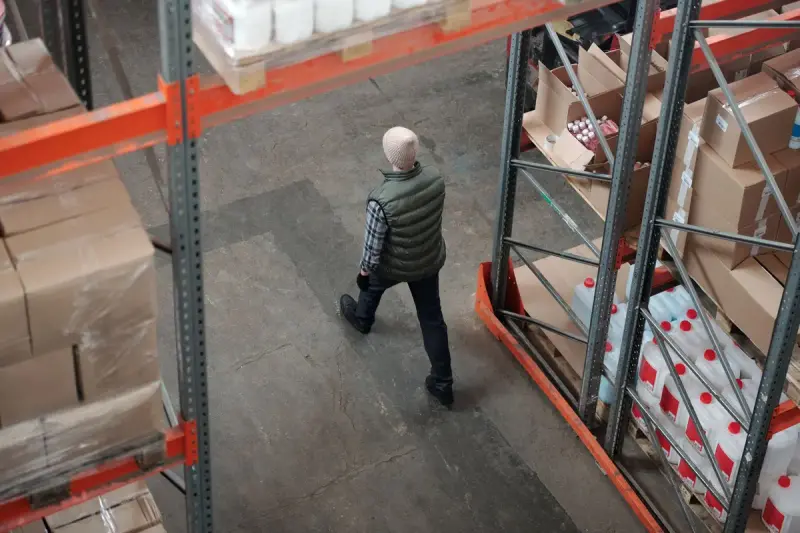 Overhead view of a worker walking between racks stacked with cartons