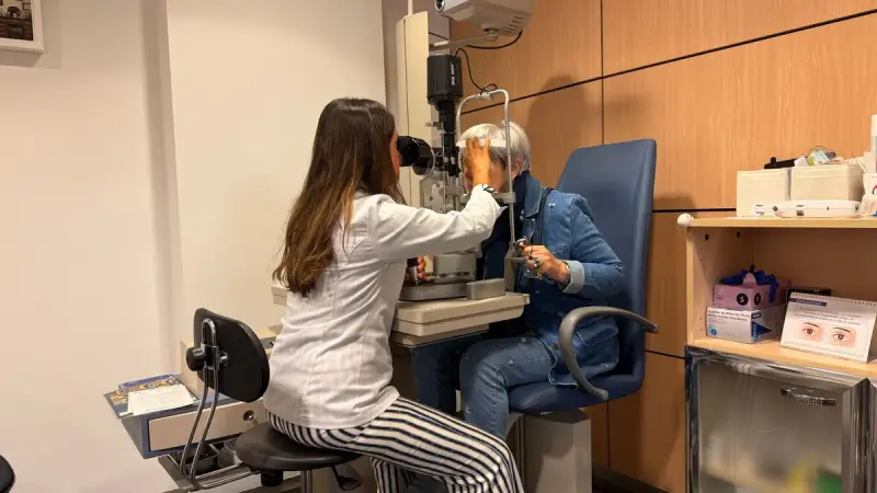Optometrist examining a patient with a slit lamp in a bright exam room