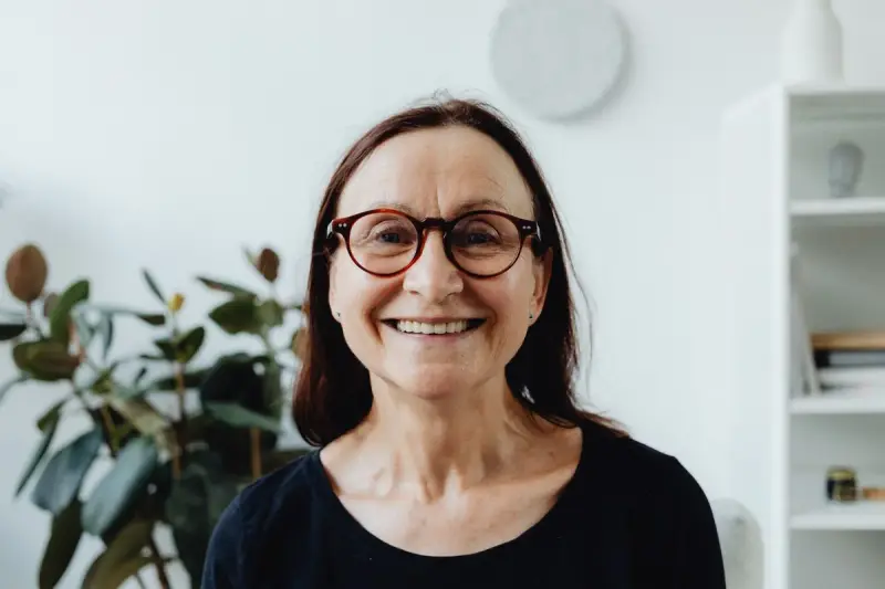 Smiling older woman in tortoiseshell eyeglasses at home