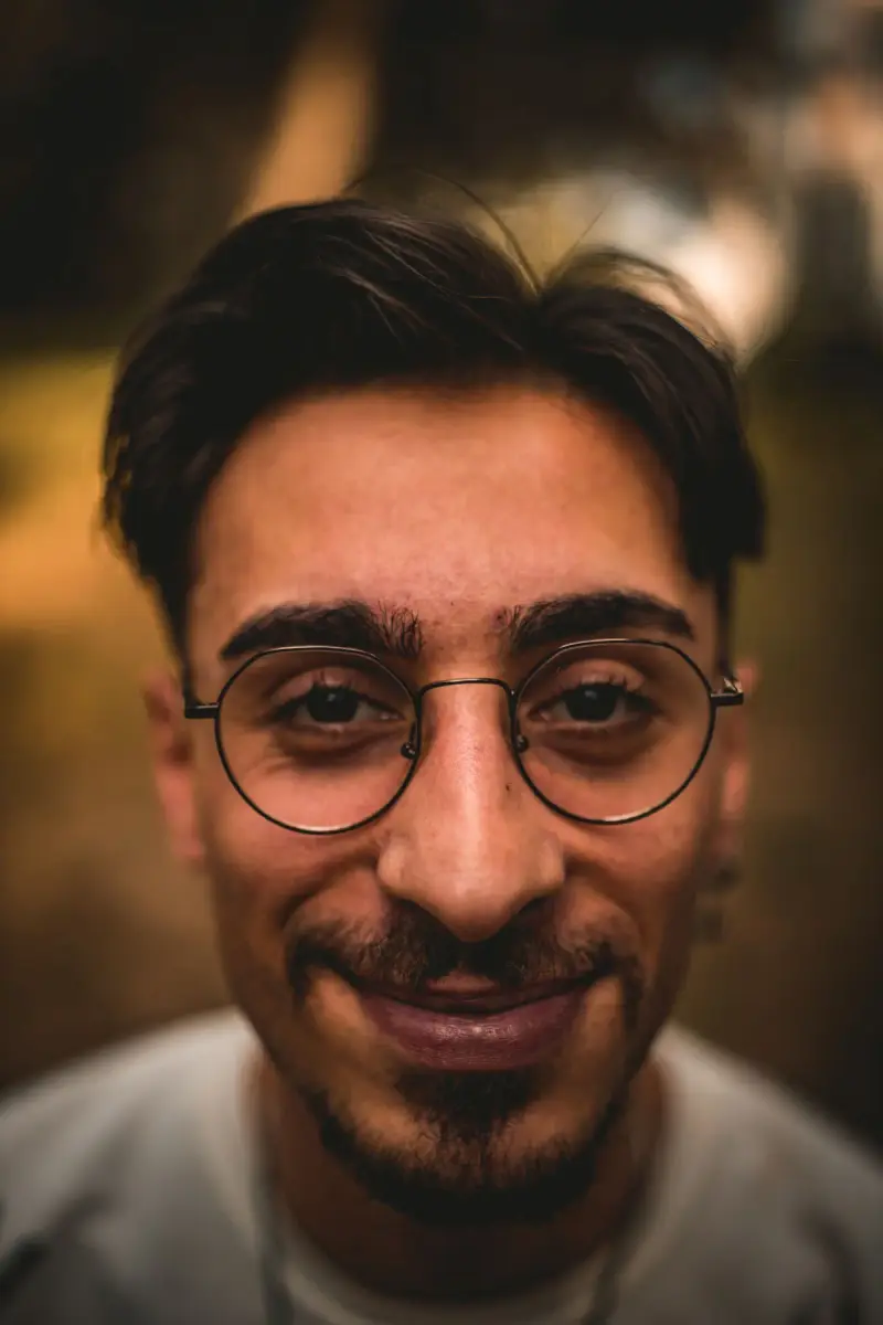 Smiling man in round metal eyeglasses, warm close-up portrait