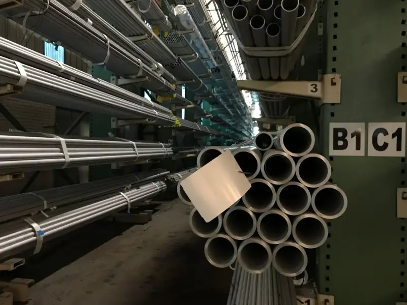 Rows of steel tubes stored on racks in a warehouse