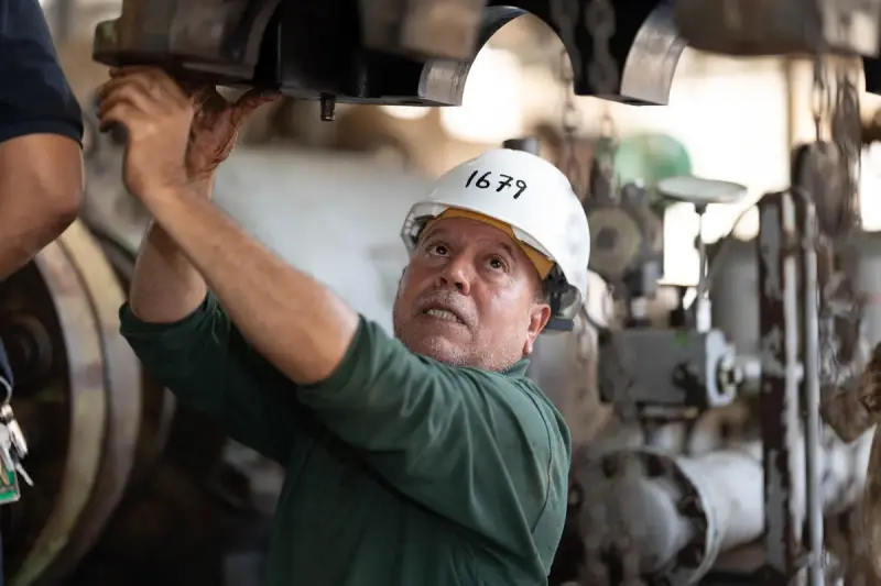 Engineer in a white hard hat inspecting machinery overhead