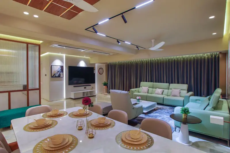 Open-plan living and dining room with mint sofas, a set dining table and track lighting