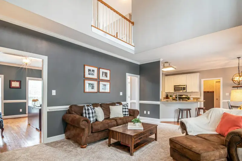 Two-story living room with leather sofas, a wooden coffee table and an open kitchen