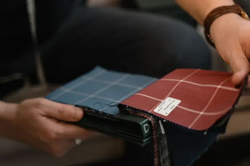 Hands holding a book of blue and red plaid upholstery fabric swatches