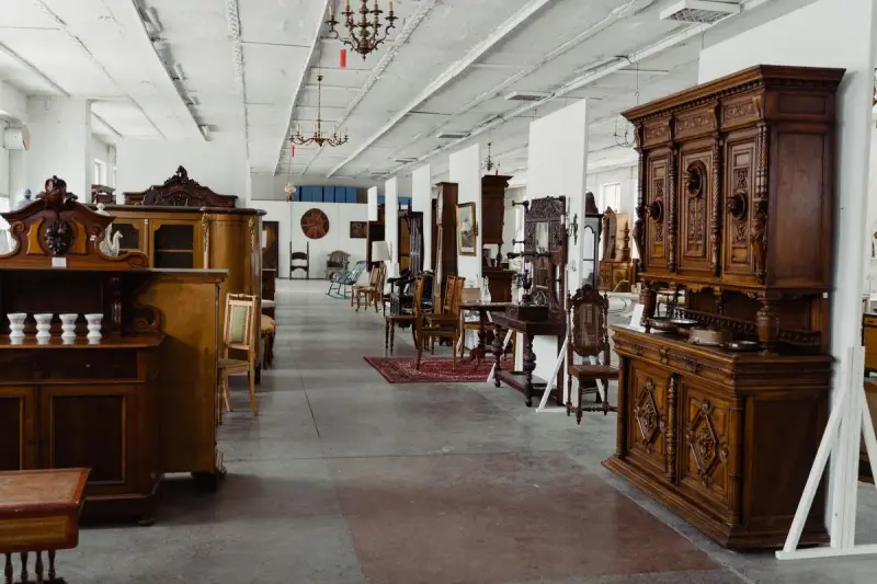 Long white-ceilinged hall filled with carved wooden cabinets, sideboards and chairs