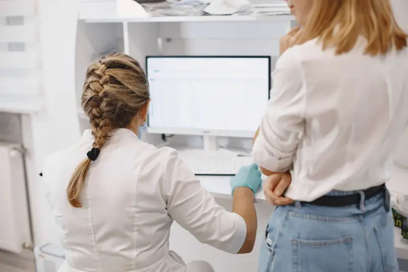 Two women healthcare professionals working together at a computer in a hospital office