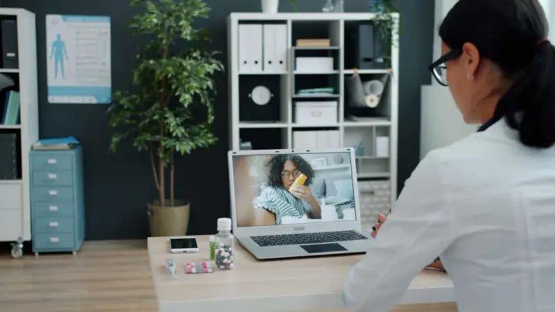 Doctor holding a virtual appointment with a patient on a laptop in an office