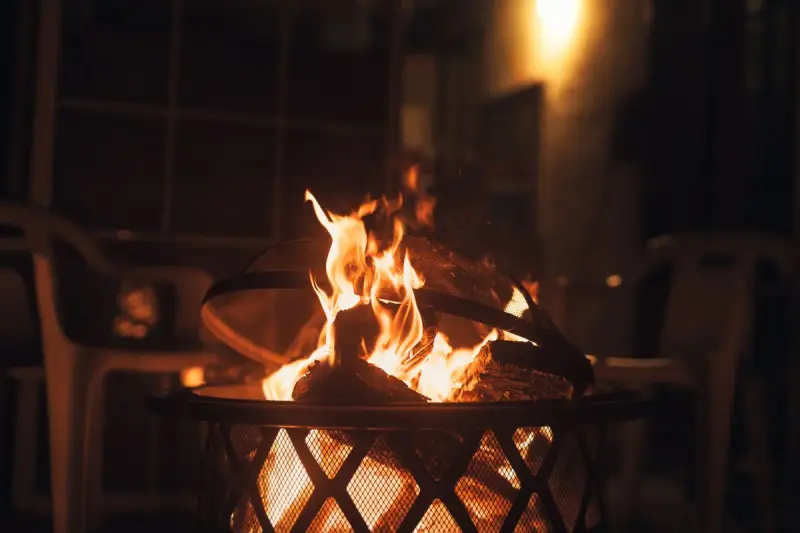 Flames rising from a steel fire basket on a patio at night