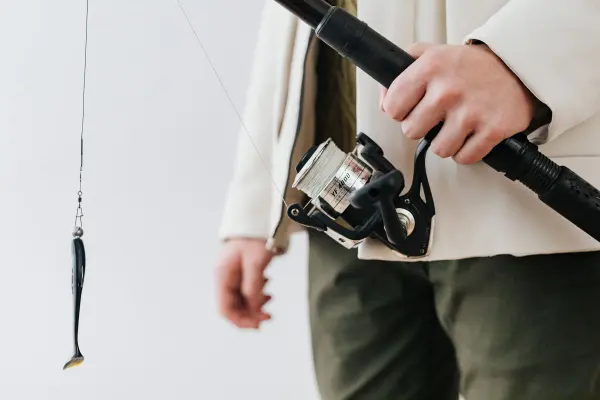 A hand holds a fishing rod with a lure and reel.