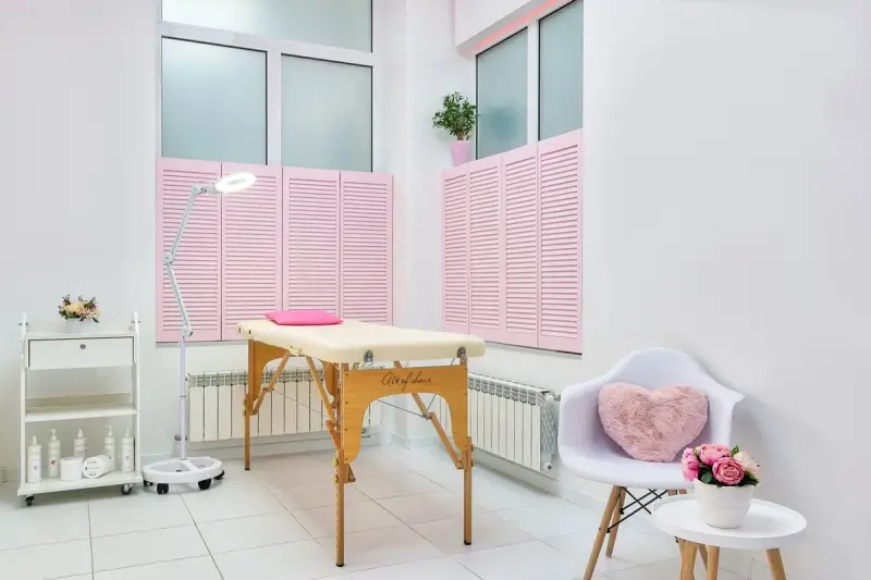 Bright esthetics treatment room with a padded bed, side chair and calm decor