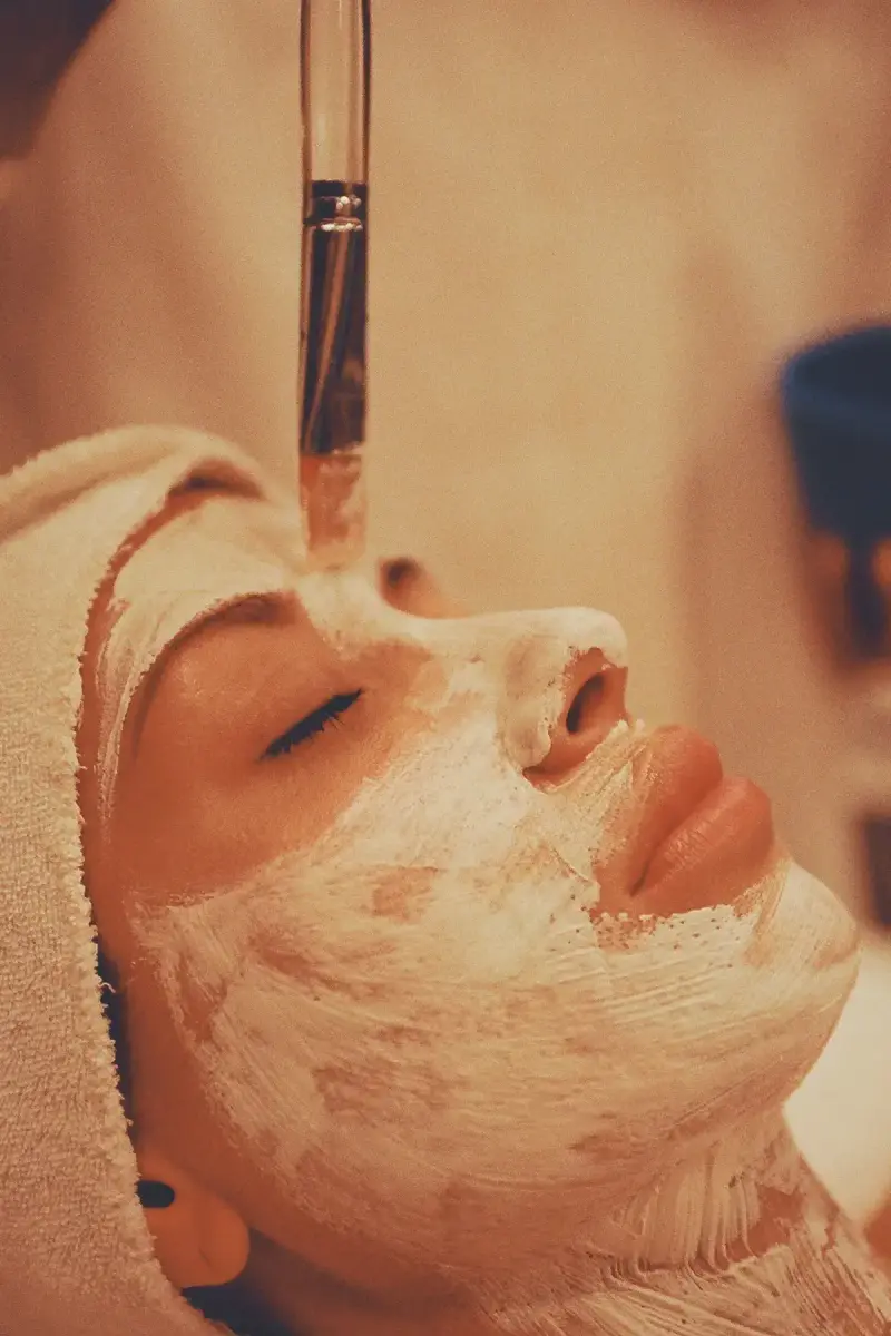 Fan brush applying a peel-style cream mask to a client's face