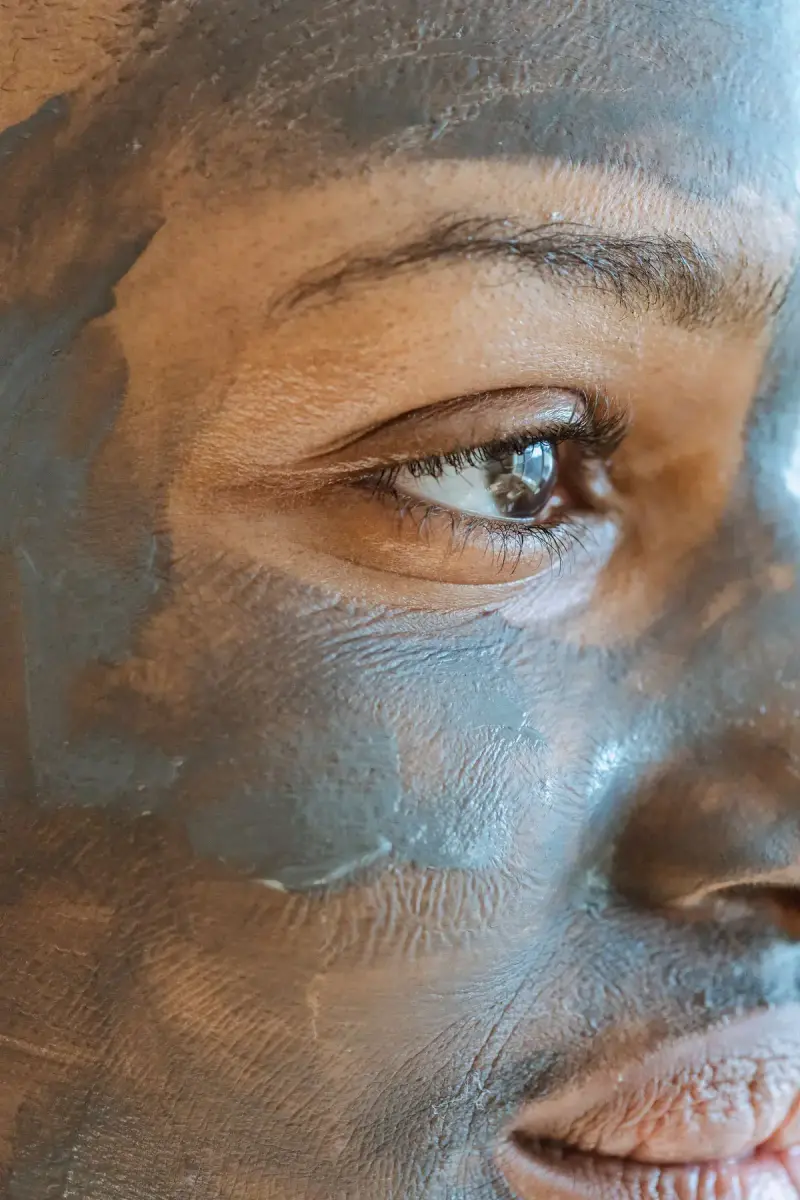 Close-up of a woman's face with a grey clay mask