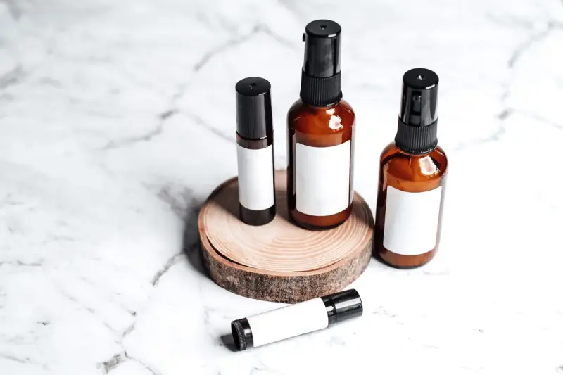 Amber pump and dropper bottles with blank labels on a wood slice over marble