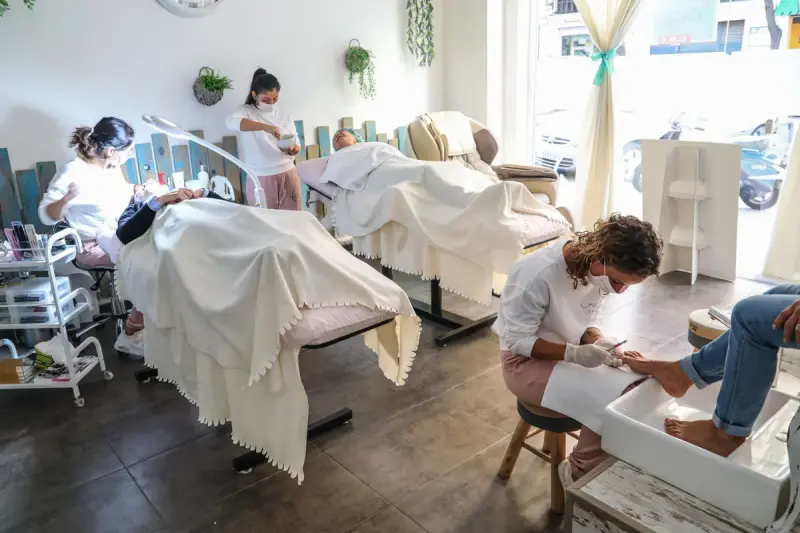 Spa professionals giving a facial and a pedicure side by side in a bright salon