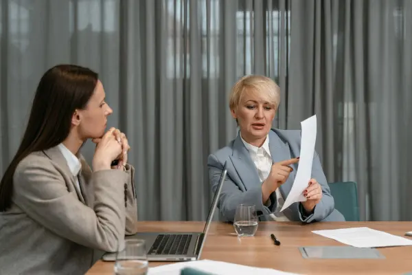 Two businesswomen reviewing documents across a conference table