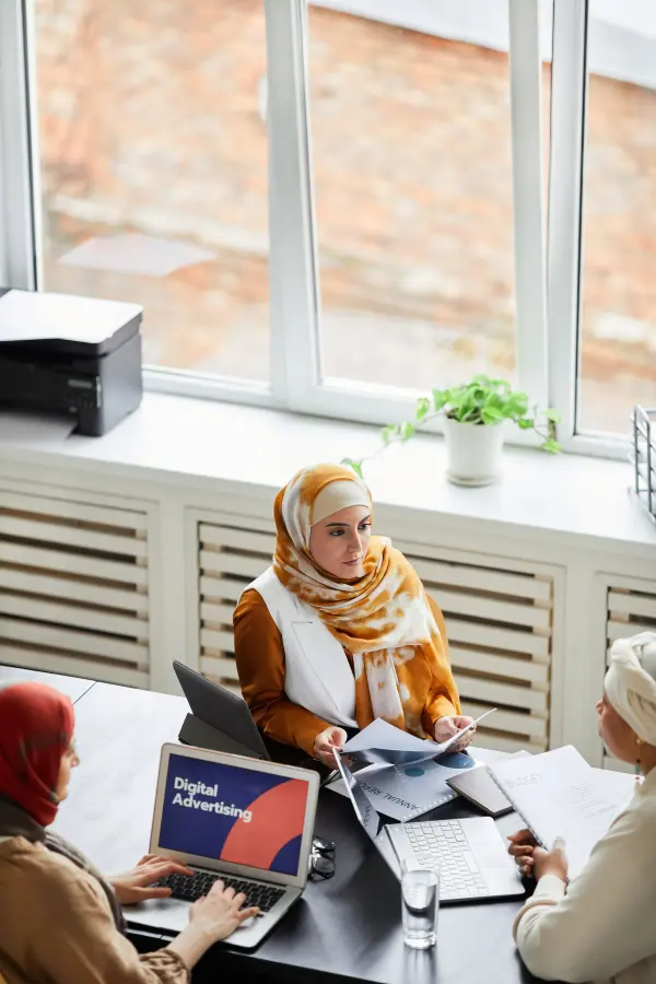 Three women collaborating around laptops and documents