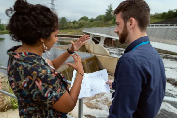 Engineers discuss plans beside a hydropower installation. Energy- photograph.