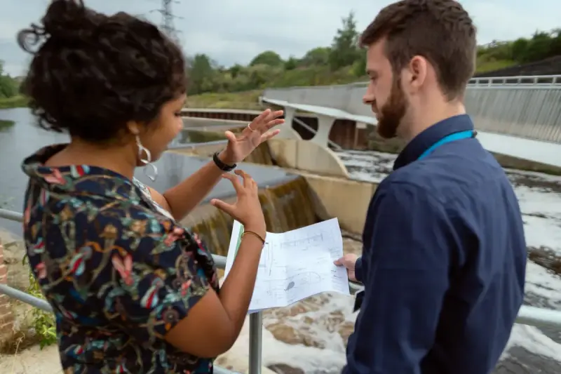 Engineers discuss plans beside a hydropower installation. Energy- photograph.