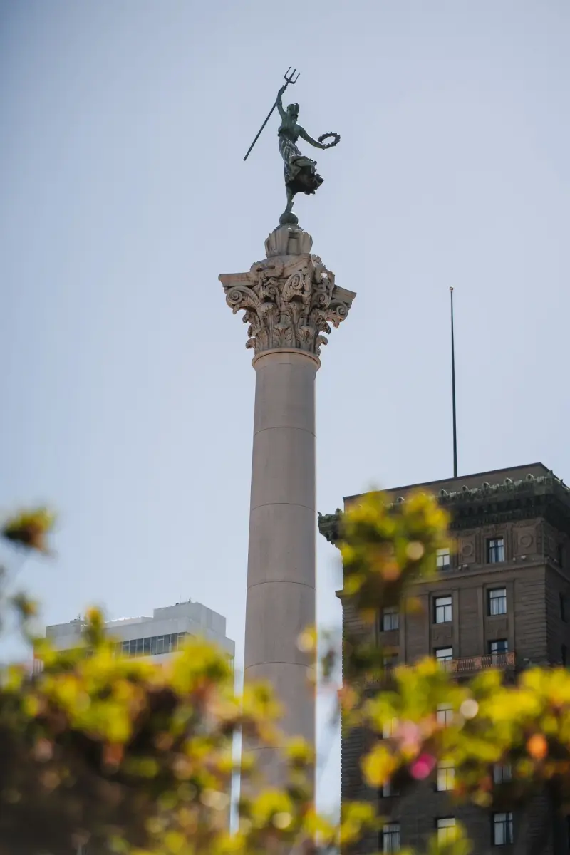 Dewey Monument column in Union Square, San Francisco, framed by trees and buildings