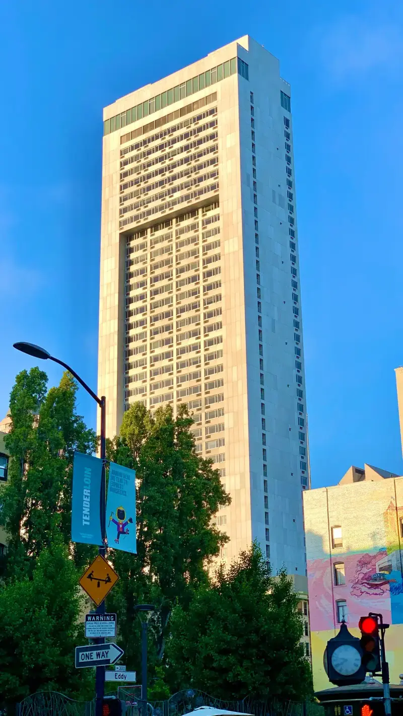 The tall white tower of the Hilton San Francisco Union Square rising above street trees