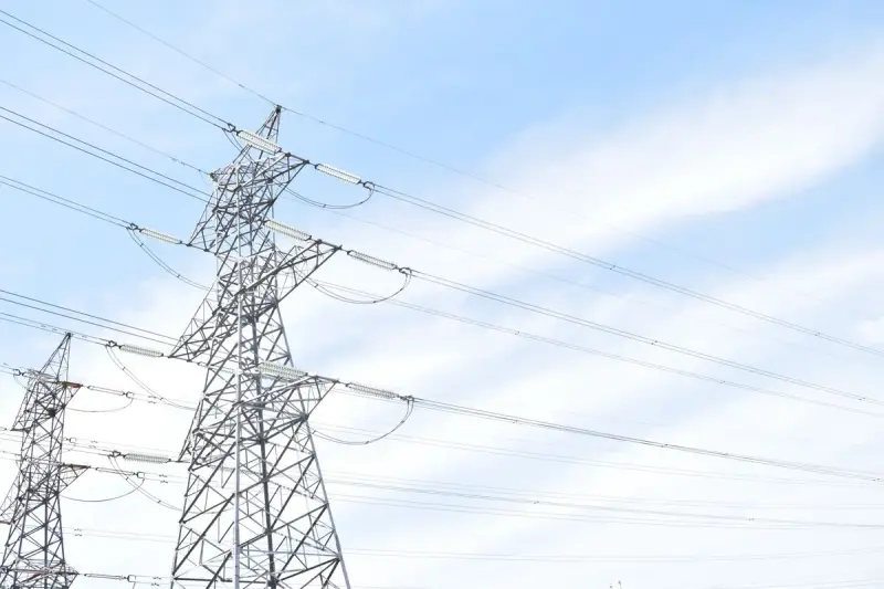 Two steel transmission towers with crossing conductors under a pale sky