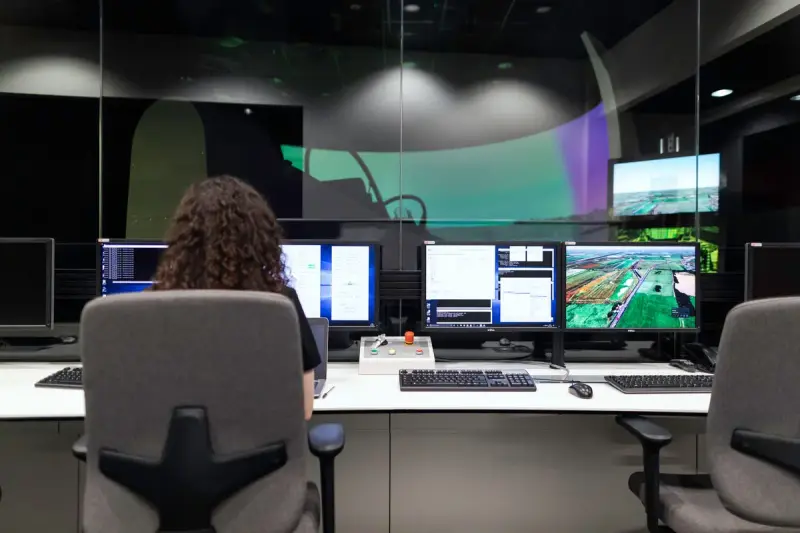 Engineer seated at a bank of monitors in a large control room