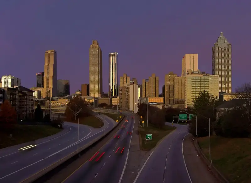 Downtown Atlanta skyline glowing at dawn above the parkway, seen from the Jackson Street Bridge