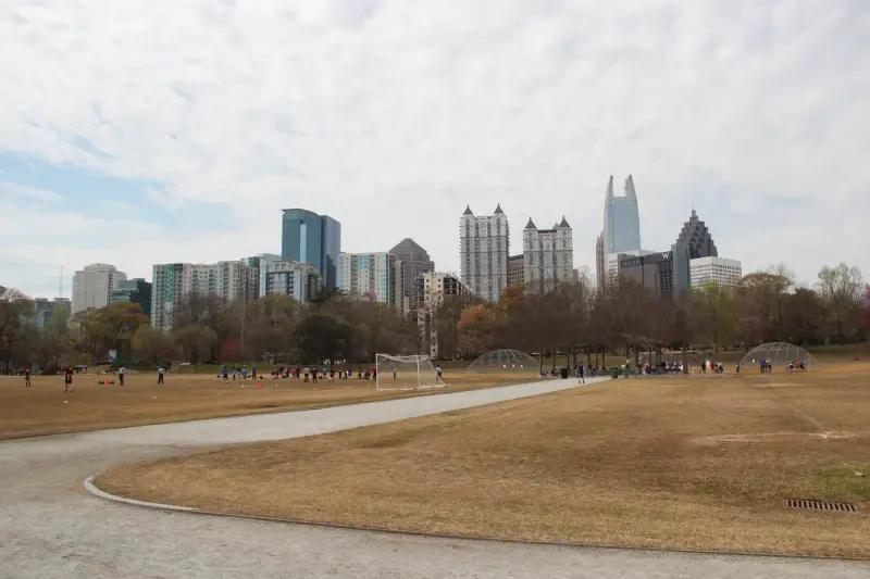 Midtown Atlanta skyline seen across the open meadow of Piedmont Park in early spring
