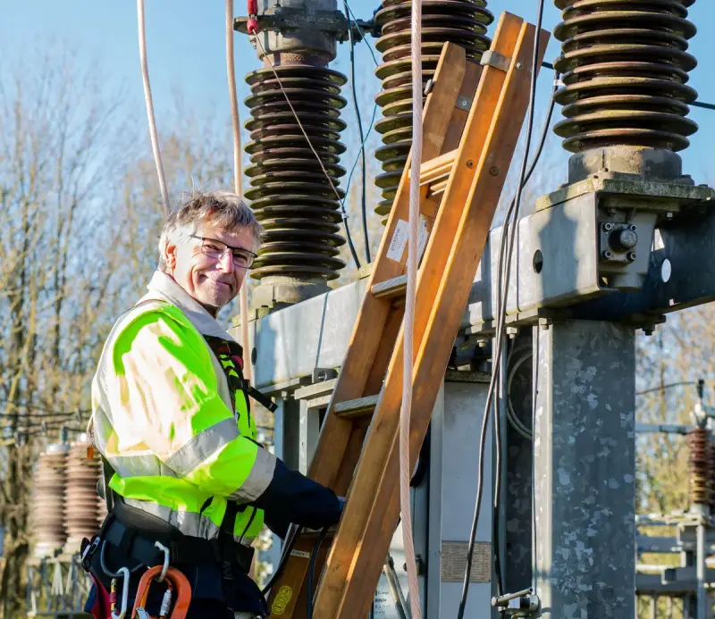 Electrician climbing a ladder at a power substation