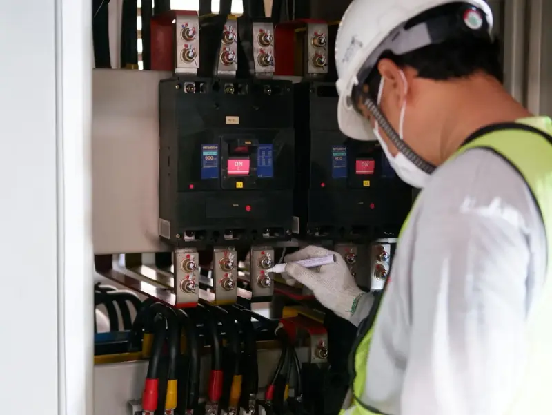 Technician in safety gear checking a power voltage reading