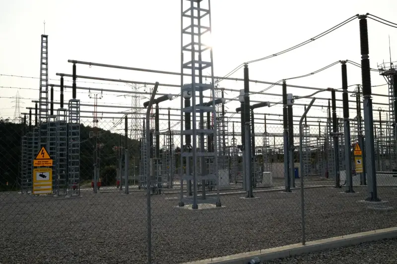 Fenced outdoor switchyard with high-voltage equipment and power lines
