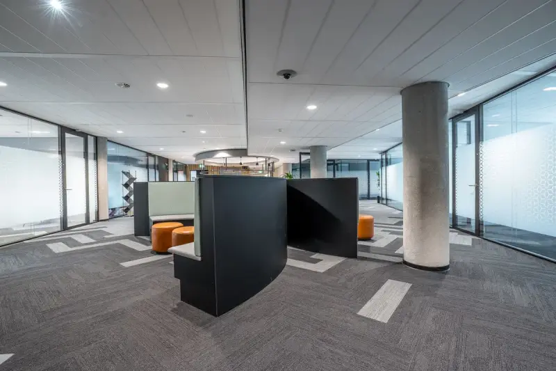 Open office floor with focus booths, glass meeting rooms and concrete columns