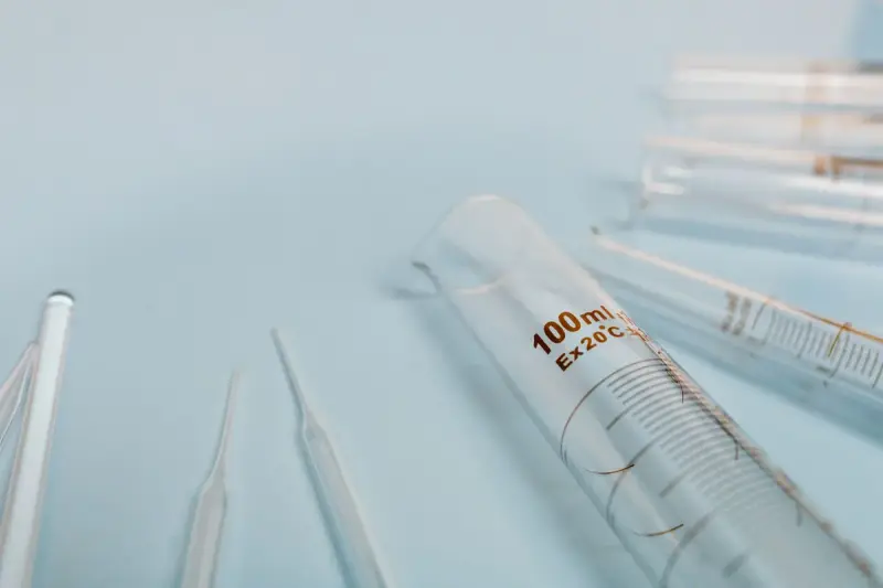 Graduated glass cylinder and pipettes lying on a pale blue surface