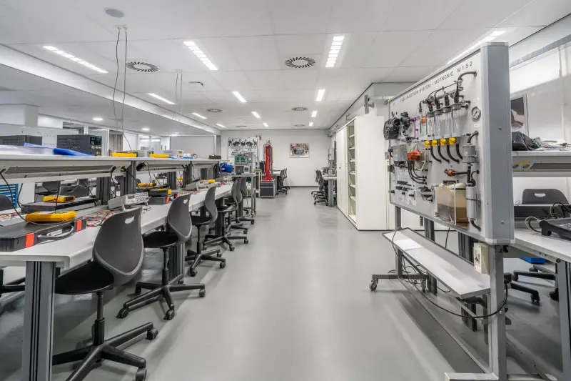 Long modern laboratory with rows of workbenches, tool panels and instrument stations