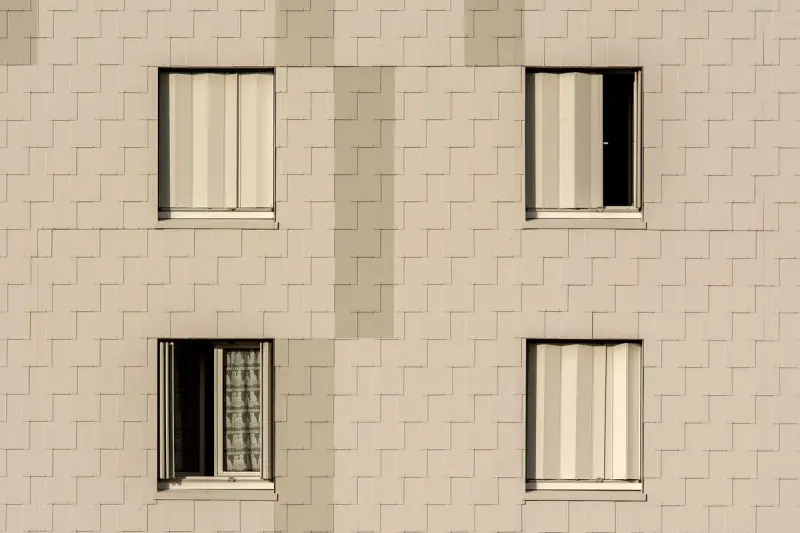 Beige stone-look facade panels with recessed windows in a tight grid