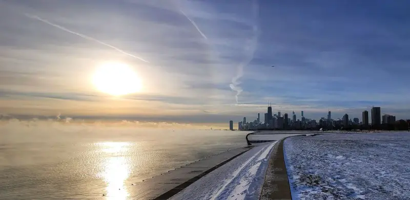 Chicago skyline beyond a frozen Lake Michigan shoreline at sunrise