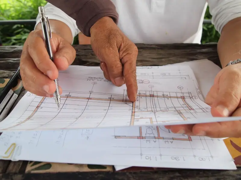 Two designers reviewing detailed plans on a table