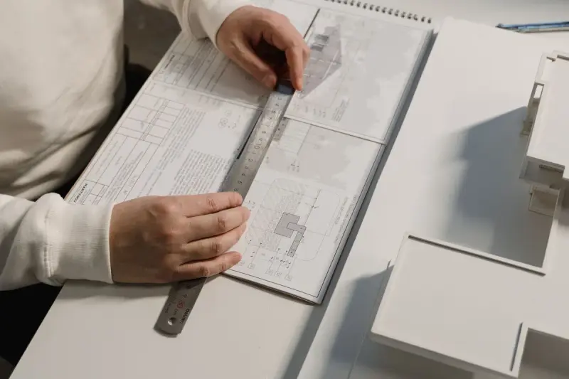 Hands drafting a design plan with a pencil and metal ruler