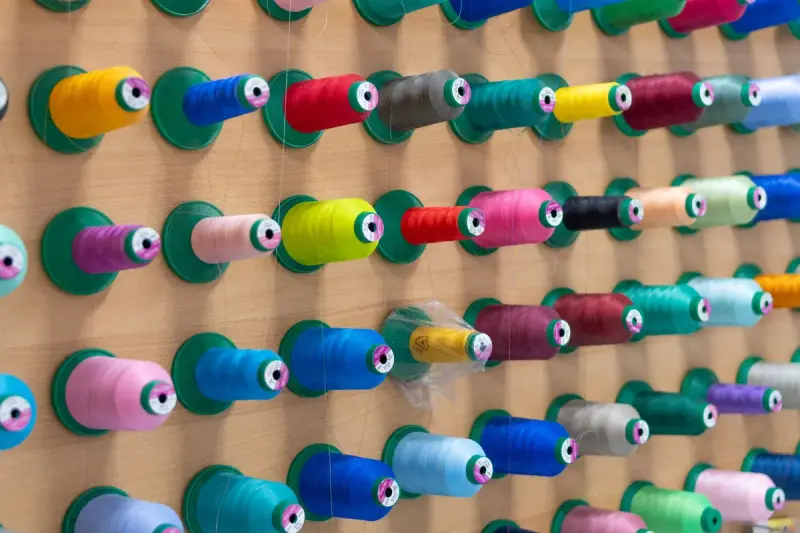 Wall of embroidery thread cones in rows of bright colors on pegs