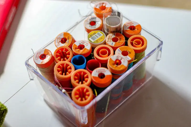 Clear box packed with orange, red and blue thread spools